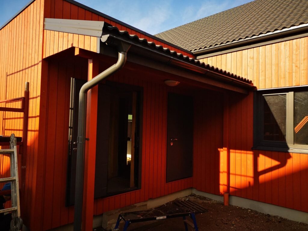 Rode houten gevelbekleding met nieuwe dakgoot